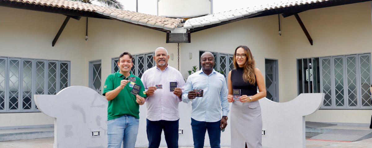 Quatro pessoas em pé, seguram o cartão Mais Aracaju Turista em frente ao Mirante da 13 de Julho